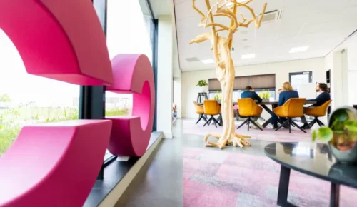 : vergaderende mensen aan tafel in kantoor met logo in voorgrond.